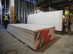 Construction workers move sheets of drywall at a building project in Calgary, Alta., Friday, Dec. 30, 2016. Anti-dumping duties on U.S. drywall imports into Western Canada have hiked prices for the building product but have also resulted in new manufacturing jobs, says the company whose complaint prompted the trade tariffs. CertainTeed Gypsum Canada has added about 30 employees since duties began in September at its drywall plants in Vancouver, Calgary and Winnipeg to boost production, said spok