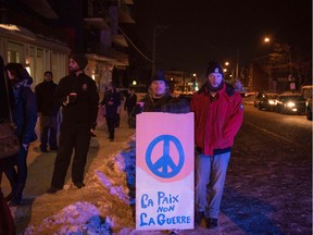 People stand with a peaceful sign near the Québec City Islamic cultural centre after a shooting occurred in the mosque on Sainte-Foy Street in Quebec city on January 29, 2017.