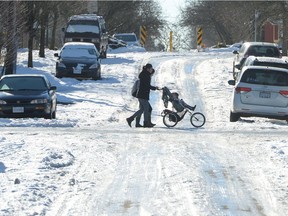 A woman pushes a stroller on an ice-covered street in Vancouver, Tuesday, Jan.3, 2017. An unusual bout of snowy winter weather has confounded residents of southern British Columbia, resulting in unplowed streets, icy sidewalks and grumbling residents who have to drive or walk in the chaos.