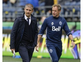 Vancouver Whitecaps head coach Carl Robinson, left, walks off the pitch with assistant coach Martyn Pert, right, after an MLS soccer match against the Seattle Sounders, Saturday, Sept. 17, 2016, in Seattle.