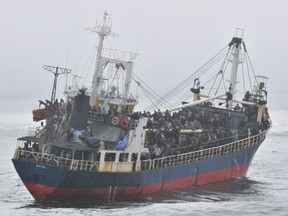 Hundreds of passengers crowd the deck of MV Sun Sea after spotting the arrival of HMCS Winnipeg off the coast of B.C. in August 2010.