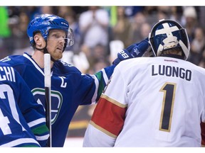 Vancouver Canucks' Henrik Sedin, left, of Sweden, taps former teammate, Florida Panthers' goalie Roberto Luongo on the head after scoring a goal against him to record his 1,000th career point.