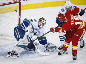 Vancouver Canucks goalie Jacob Markstrom, left, of Sweden, grabs for the puck as Calgary Flames' Matthew Tkachuk looks on during third period NHL hockey action in Calgary, Saturday, Jan. 7, 2017.