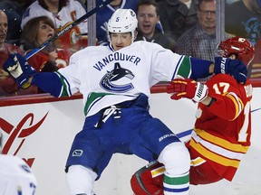 Vancouver Canucks' Luca Sbisa is checked by Calgary Flames' Lance Bouma.