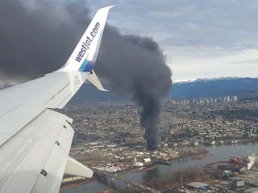 A fire at a recycling depot on Mitchell Island sends huge plumes of black smoke into the surrounding skies, Friday, Jan. 20, 2017.