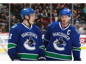 Henrik Sedin talks to teammate Bo Horvat.