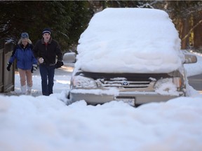 People make their way past a snow-covered vehicle on a street in Vancouver, Wednesday, Jan.4, 2017.