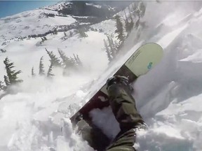 A screen grab from Tom Oye's video showing the snowboarder getting swept down a steep slope by an avalanche.