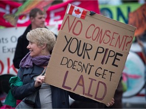 A woman holds a sign during a protest and march against the Kinder Morgan Trans Mountain Pipeline expansion, in Vancouver, B.C., on Saturday November 19, 2016.