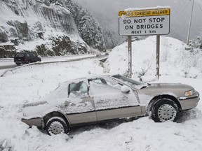 Squamish  RCMP member inspects a car in the ditch along the Sea-to-Sky highway north of Lions Bay Friday, January 6, 2017. Ice and packed snow made for hazardous road conditions on the highway causing several accidents.