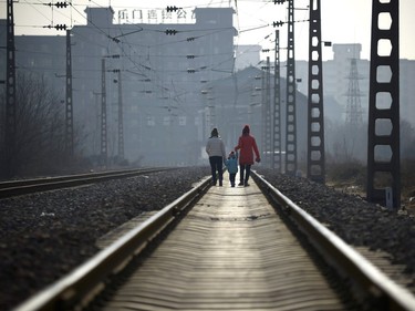 Two women carrying a child walk along a railway in Beijing on January 12, 2017.