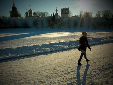 A woman walks along a snow-covered frozen pond near Moscow's Novodevichy Convent in air temperatures of about minus 10 degrees Celsius on January 11, 2017.