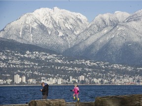 Clear, cold weather shows off the North Shore mountains as people walk along Vancouver's Locarno Beach on Monday.