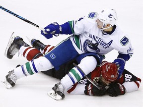 Vancouver Canucks right wing Alexandre Burrows (14) sits on Arizona Coyotes left wing Jamie McGinn (88) during the third period of an NHL hockey game Thursday, Jan. 26, 2017, in Glendale, Ariz. The Coyotes defeated the Canucks 3-0.