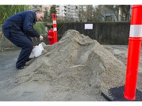 Brandon Ma fills a bucket with sand and salt on Thursday from the pile at Vancouver Fire Department's Hall No. 7 at 1090 Haro St.