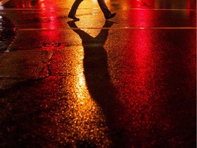 A pedestrian walks across a street during a rainy night in Vancouver on Jan. 11, 2016. Richard Lam/PNG files