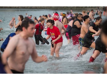 A woman, centre, reacts to the cold water while participating in the Polar Bear Swim at English Bay in Vancouver, B.C., on Sunday, January 1, 2017. The event, hosted by the Vancouver Polar Bear Swim Club, was first held on new year's day in 1920.