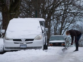 A woman uses a shovel to chip away at the ice built up on a street in Vancouver on Jan. 6.