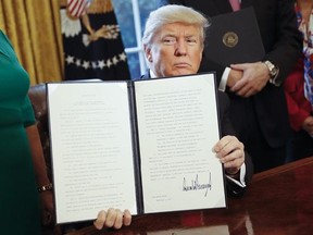 President Donald Trump holds up an executive order after his signing the order in the Oval Office of the White House in Washington, Friday, Feb. 3, 2017. The executive order that will direct the Treasury secretary to review the 2010 Dodd-Frank financial oversight law, which reshaped financial regulation after 2008-2009 crisis. (AP Photo/Pablo Martinez Monsivais)