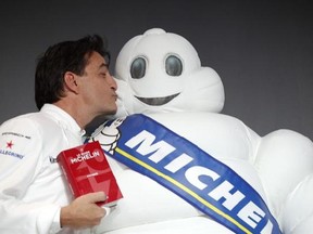 French chef Yannick Alleno who runs Le 1947 restaurant in Courchevel, gives a kiss to the Michelin Mascot known as Bibendum after being awarded three stars from the Michelin guide, Thursday, Feb.9, 2017 in Paris. One restaurant was newly awarded with the prestigious 3 stars this year. (AP Photo/Christophe Ena)