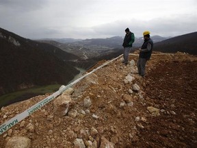 Workers survey damage after a landslide near the Bosnian town of Kakanj located 50 kms north of Sarajevo on Friday, Feb. 24, 2017. More than 150 people have been forced to evacuate their homes in central Bosnia due to a major landslide at an open pit coal mine that threatened to bury their villages. (AP Photo/Amel Emric)