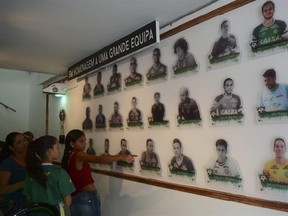 In this Feb. 18, 2017, file photo, young visitors point at photos of players of Brazil&#039;s Chapecoense team who died in plane crash last year, at a bar opened in their honor in Medellin, Colombia. The tragedy shook the soccer world and resonated especially strongly in this Andean city where for one Colombian couple, the best way to pay homage to the players was to open a bar named for the team. (AP Photo/Luis Benavides)