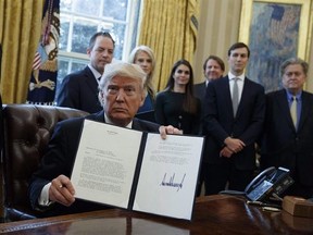 President Donald Trump shows his signature on an executive order on the Keystone XL pipeline, Tuesday, Jan. 24, 2017, in the Oval Office of the White House in Washington. TransCanada Corp. has suspended a $15-billion lawsuit against the United States regarding its Keystone XL project following signals by U.S. President Donald Trump that he will likely approve the pipeline. THE CANADIAN PRESS/AP/Evan Vucci