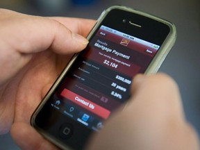 A smartphone user checks their bank account with an online banking app from CIBC.