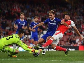 Arsenal's French striker Olivier Giroud (R) stretches to try to reach the ball as Chelsea's Belgian goalkeeper Thibaut Courtois (L) and Chelsea's Serbian defender Branislav Ivanovic (C) defend during the English Premier League football match between Arsenal and Chelsea at the Emirates Stadium in London on September 24, 2016.  /