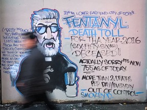 A man walks past a mural by street artist Smokey D. about the fentanyl and opioid overdose crisis in the Downtown Eastside.