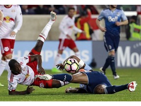 New York Red Bulls forward Bradley Wright-Phillips, left, trips over Vancouver Whitecaps defender Kendall Waston inside the Whitecaps box during the first half of a CONCACAF Champions League quarterfinal soccer match, Wednesday, Feb. 22, 2017, in Harrison, N.J.