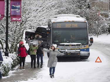 People throw snowballs as a bus is stuck on the road in North Vancouver, B.C., Friday, Feb. 3, 2017. A snowstorm hit the northshore leaving cars and trucks slipping and sliding.