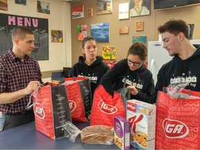 Community school coordinator Brad Hendy receives his school's weekend allotment of food for hungry students brought in by Katrina Schulz, sister Emma and their cousin, Brady Lumsden, founders of Weekend Fuel.