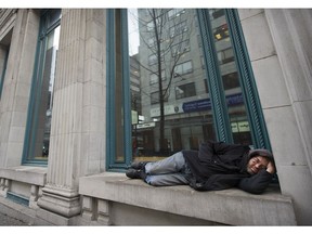 A man sleeps on the window ledge in front of the SFU building in downtown Vancouver. The region's homeless and drug issues continue to grow in the Metro Vancouver area.