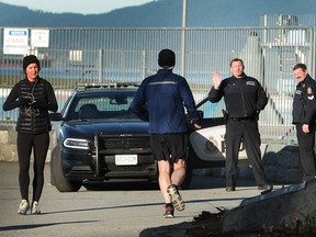 Vancouver police redirect joggers away from the scene of the Wednesday-night homicide by the Stanley Park seawall.