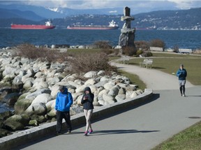 People enjoy the blue, clear skies over English Bay in Vancouver, BC