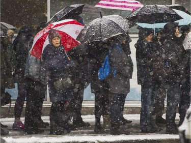 People wait for buses on East Broadway near Commercial during Friday's snowstorm in Vancouver, B.C., February 3, 2017.