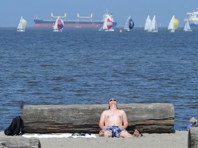 Beach goers soak in the sun with a backdrop of sailboats at Kitsilano Beach in Vancouver July 8, 2012.