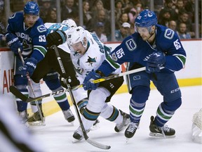 Vancouver Canucks right wing Alexandre Grenier (65) fight for control of the puck with San Jose Sharks center Logan Couture (39) during first period NHL action Vancouver, B.C. Saturday, Feb 25, 2017. THE CANADIAN PRESS/Jonathan Hayward ORG XMIT: JOHV102