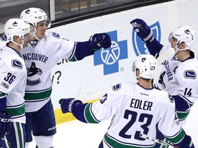 Bo Horvat (53) of the Vancouver Canucks celebrates with Jannik Hansen (36), Alexander Edler (23) and Alexandre Burrows (14) after scoring against the Bruins at TD Garden on Saturday in Boston.