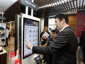 FILE - In this Thursday, Nov. 17, 2016, file photo, McDonald&#039;s CEO Steve Easterbrook demonstrates an order kiosk, with cashier Esmirna DeLeon, during a presentation at a McDonald&#039;s restaurant in New York&#039;s Tribeca neighborhood. McDonald‚Äôs has started testing mobile order-and-pay after acknowledging the ordering process in its restaurants can be ‚Äústressful.‚Äù The company is testing the option in California and Washington ahead of a national launch in the U.S. toward the end of 2017. Easterbr