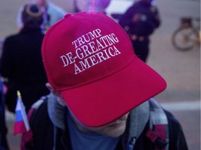 A man wears a hat that reads 'Trump De-Greating America' as people gather for a protest against U.S. President Donald Trump's new travel-ban order in Lafayette Park outside the White House on March 6 in Washington, D.C.