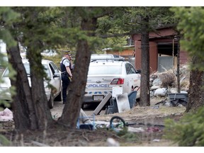 A police officer is seen in the driveway of a house in Venables Valley near Ashcroft, on Sunday. Four people were found dead in a home in a remote community in the B.C. Interior, RCMP said Saturday.