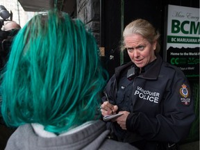 A police officer speaks with an employee outside the Cannabis Culture shop during a police raid, in Vancouver, B.C., on Thursday March 9, 2017. Prominent marijuana activists Marc and Jodie Emery have been arrested in Toronto and police are raiding several pot dispensaries associated with the couple.