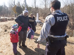 A refugee family, who claim to be from Colombia, are arrested by an RCMP officer as they cross the border from New York into Canada.