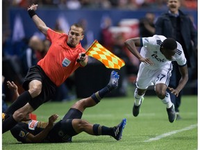 Philadelphia Union's Fabinho, bottom left, collides with assistant referee Adam Wienckowski after knocking Vancouver Whitecaps' Alphonso Davies, right, off the ball during the second half of an MLS soccer game in Vancouver, B.C., on Sunday March 5, 2017.