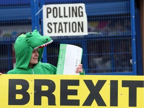 A Sinn Fein election worker dressed up as a crocodile stands behind a banner referring to Brexit outside a polling station in Belfast.