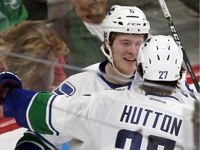 Vancouver Canucks' Brock Boeser, left, who was signed on Friday, is congratulated by Ben Hutton after Boeser scored against Minnesota Wild goalie Darcy Kuemper as he made his NHL debut during the second period of an NHL hockey game Saturday, March 25, 2017, in St. Paul, Minn.