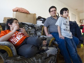 Single father Martin Fernandez watches TV in his apartment with his two young sons, Samuel and Isaias.