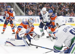 Oilers goalie Cam Talbot makes a save as Markus Granlund and Bo Horvat look for an opening.